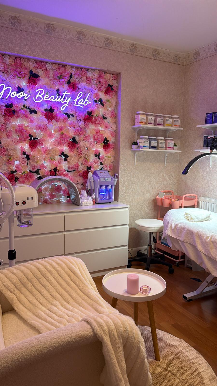Noor Beauty Lab studio - cosy treatment room with pink flower wall and neon sign